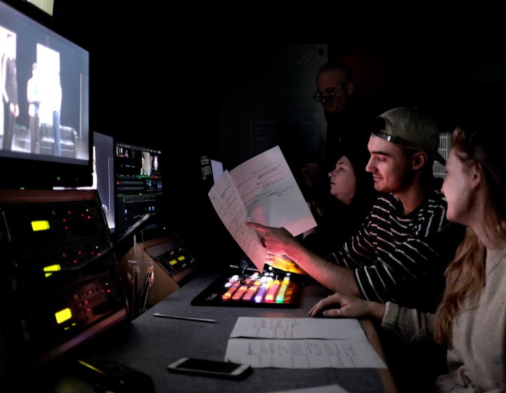 Two Film students at Falmouth University sat behind a large screen, editing