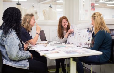 Falmouth University students discussing work on boards in a studio.