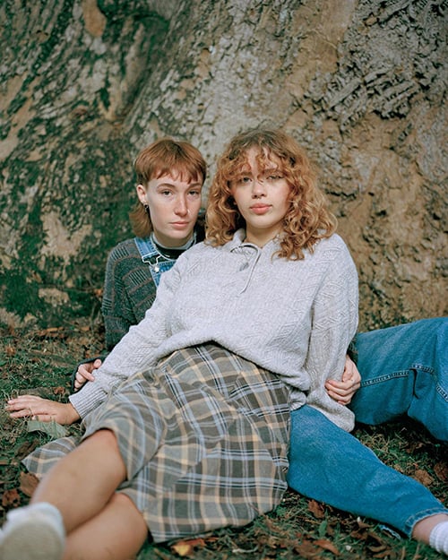 Two young women sitting in woodland