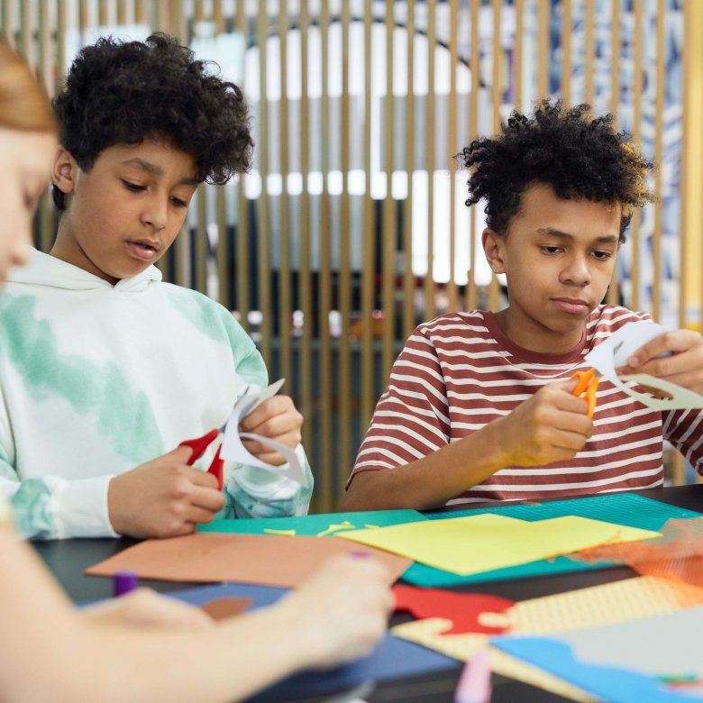 Young adults cutting out pieces of coloured paper