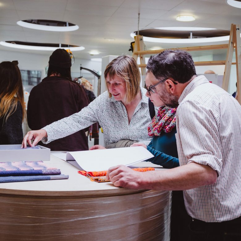 A girl with her parents looking through sketchbooks at a Falmouth University Open Day