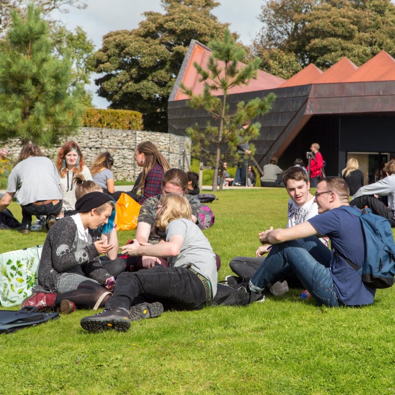 Lot's of students hanging out on the grass at Penryn campus.
