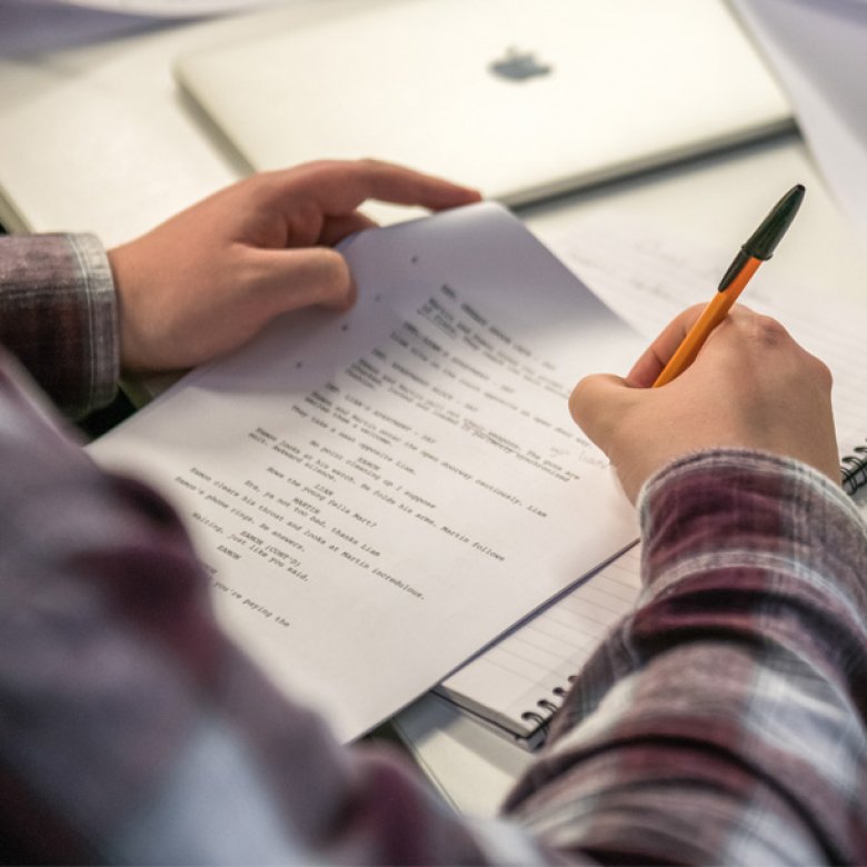 Hands holding a script and annotating it with a pen