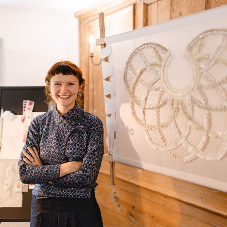 A woman stood by a large piece of embroidery