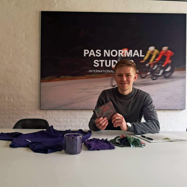 A man sat at a desk with some material samples