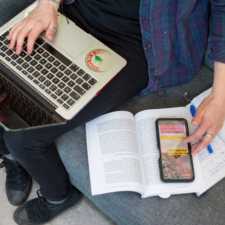 A student working on their laptop while looking at some textbooks