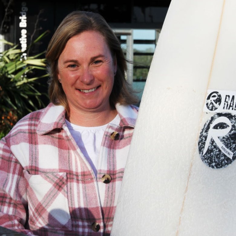 Kate with her surfboard showcasing Radical Wax branding