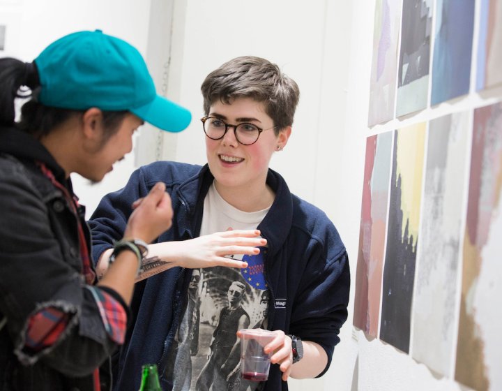 Two Falmouth University students discussing images at an exhibition.