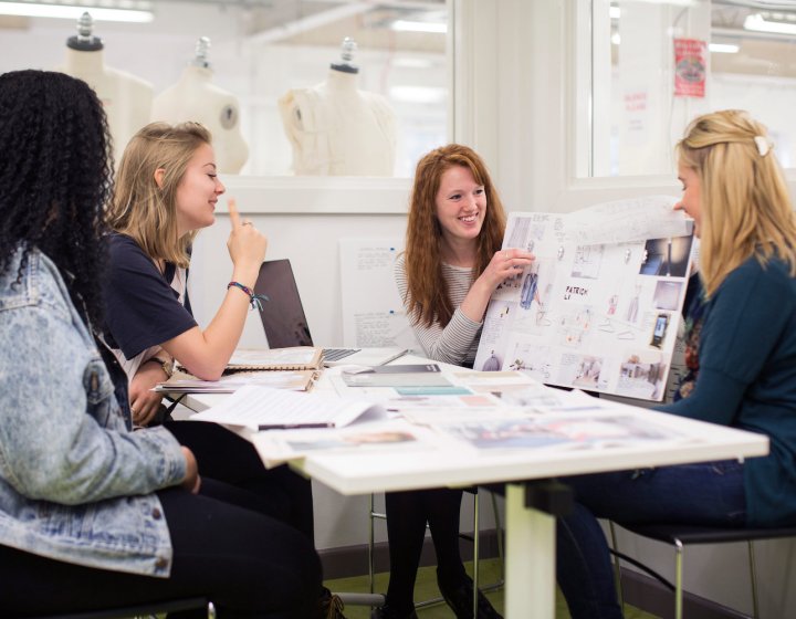 Falmouth University students discussing work on boards in a studio.