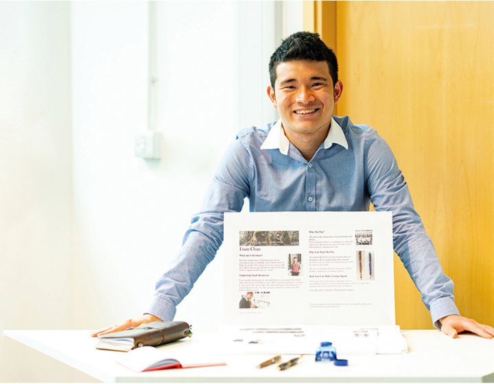 Business & Entrepreneurship student standing at a display table, smiling