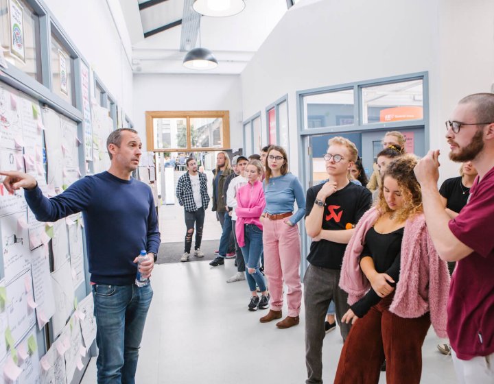 Falmouth University Creative Advertising students and lecture discussing a wall of ideas