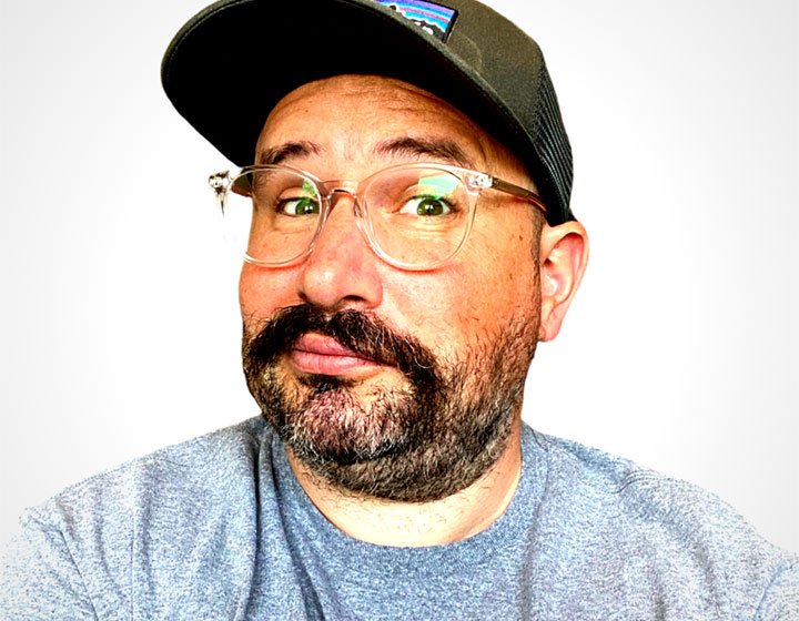 Headshot of Don't Cry Wolf founder John Brown. John wears a t-shirt and baseball cap