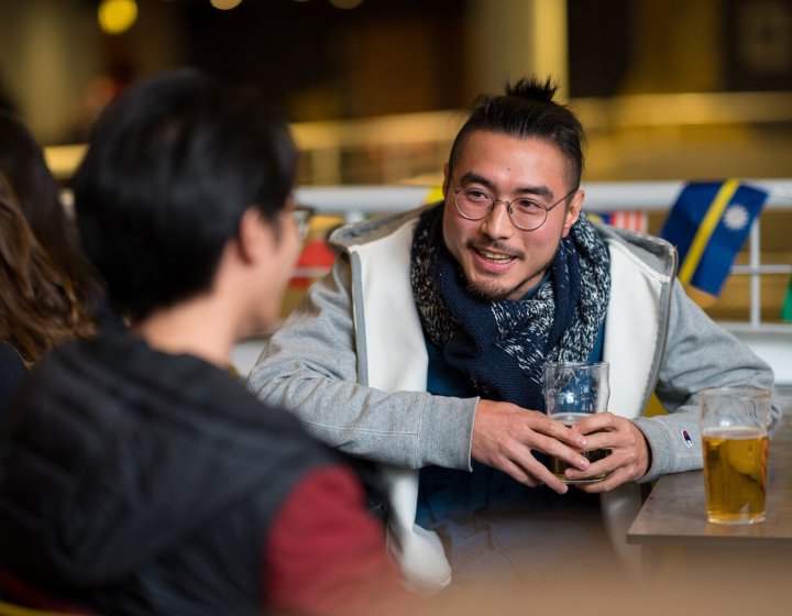 Students chatting to each other with a beer in hand.