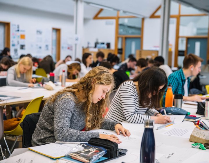 Graphic Design studio full of students busy working at desks at Falmouth University