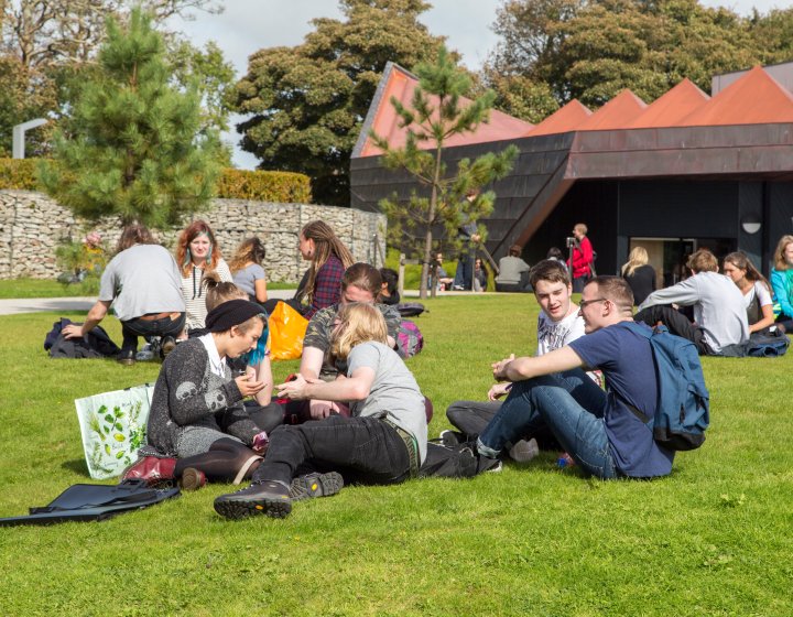 Lot's of students hanging out on the grass at Penryn campus.