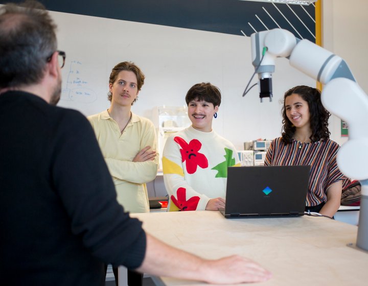 Falmouth University students listening to a lecturer around a table