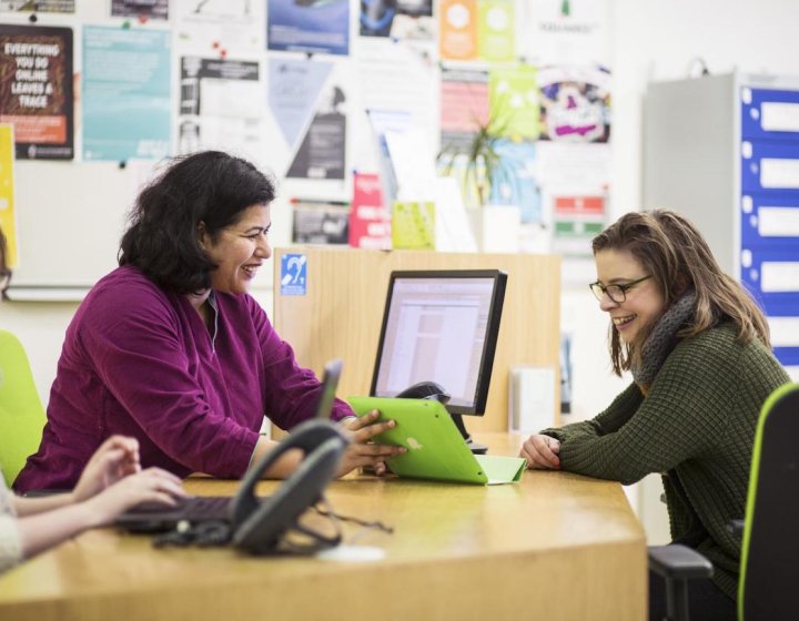 A staff member and student smiling at a desk