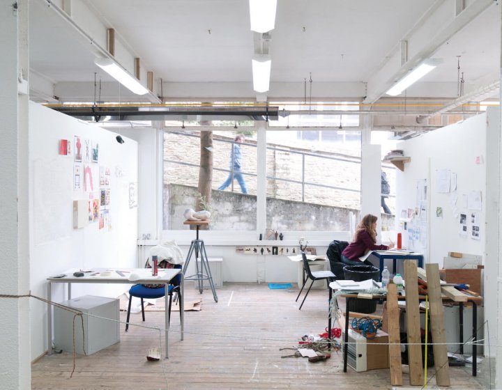 Art student working in studio with large window on Falmouth campus and person walking past and looking in.