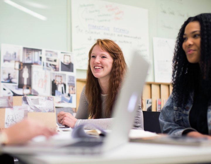 Smiling fashion marketing students working together around a desk.