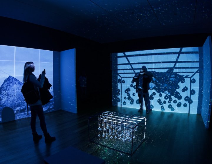 Two people standing in a dark room with blue projections