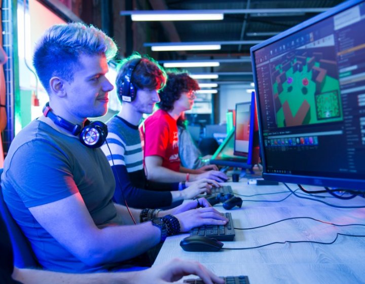 Games academy students sit side-by-side looking at computer screens