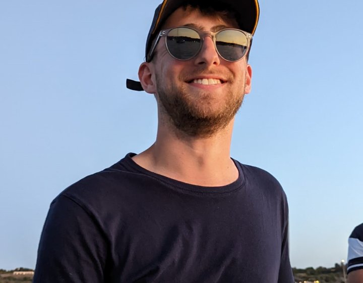 Man (Falmouth University graduate James Pearce) wearing black tshirt, sunglasses and cap