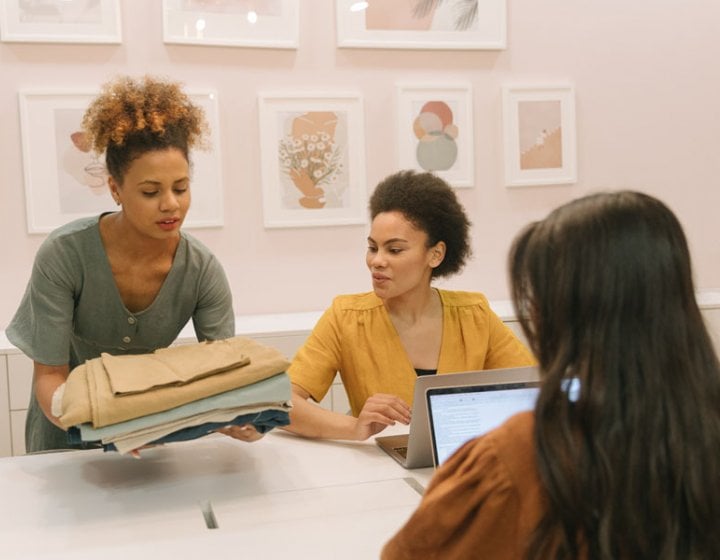 Three Sustainable Fashion students looking at fabric