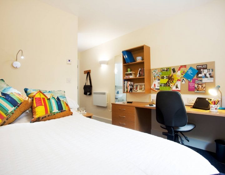 An empty university room, equipped with double bed and desk