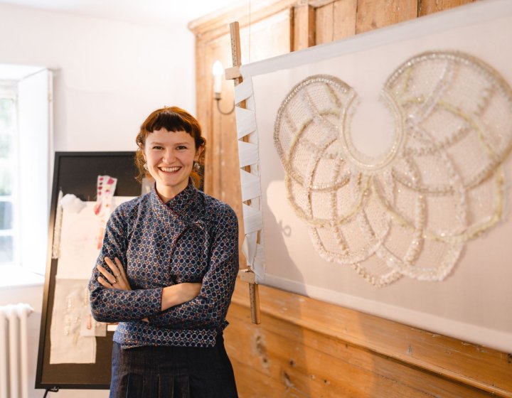 A woman stood by a large piece of embroidery