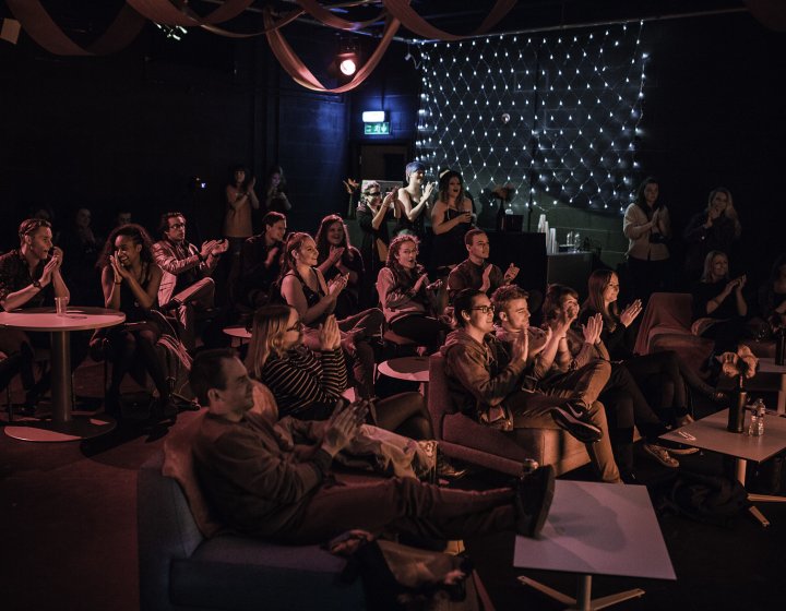 A busy venue with people watching a show and clapping