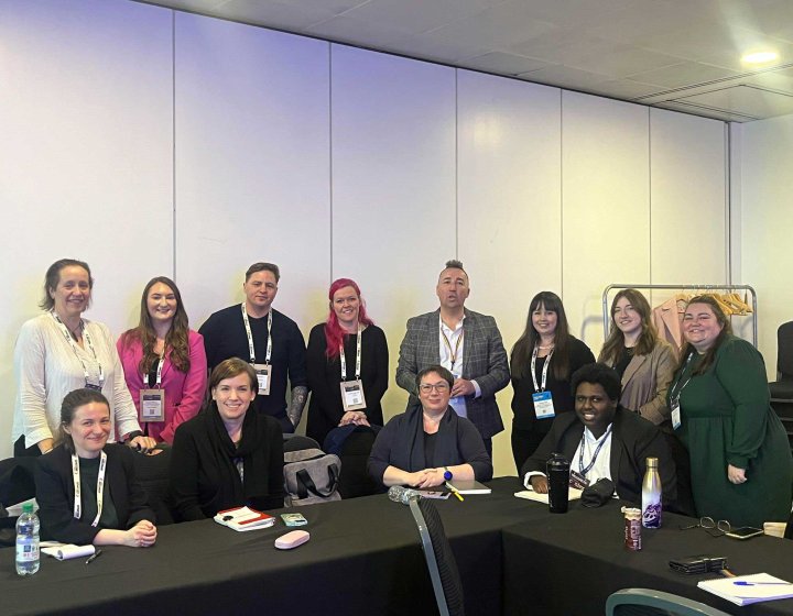 A group of students and staff sat at a table at a conference