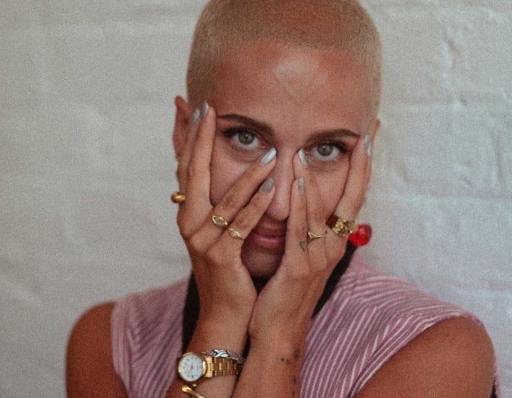 A woman smiling into the camera with her hands over her face