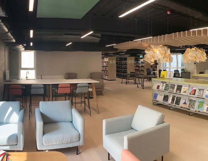 View of Falmouth University library with blue chairs and bookcases