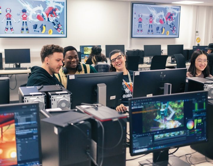 A group of people sat round computer screens