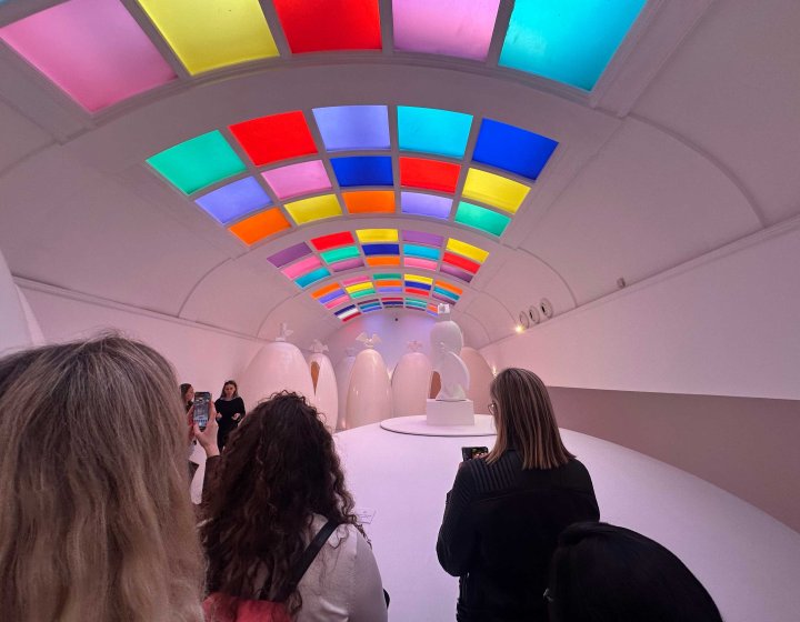 A group of people stood in a room with neon coloured ceiling panels 