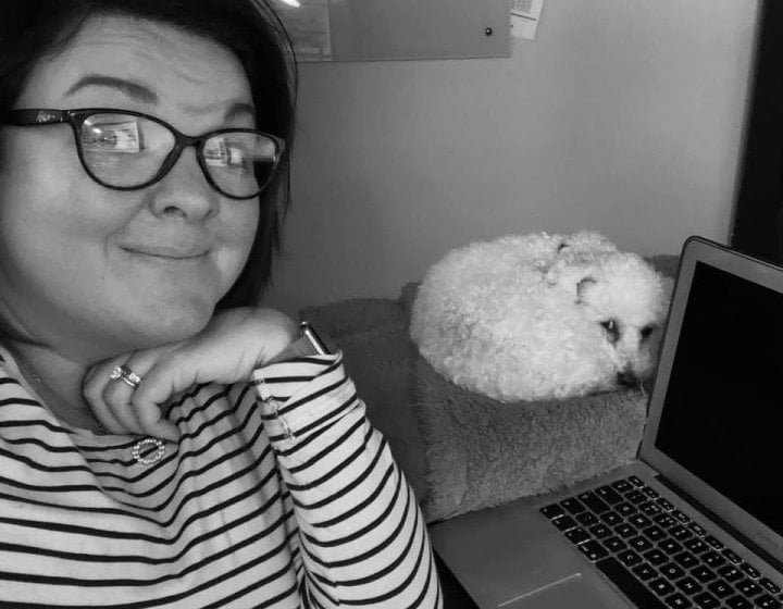 A selfie of a woman with a dog in the background