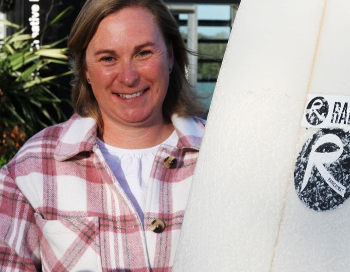 Kate with her surfboard showcasing Radical Wax branding