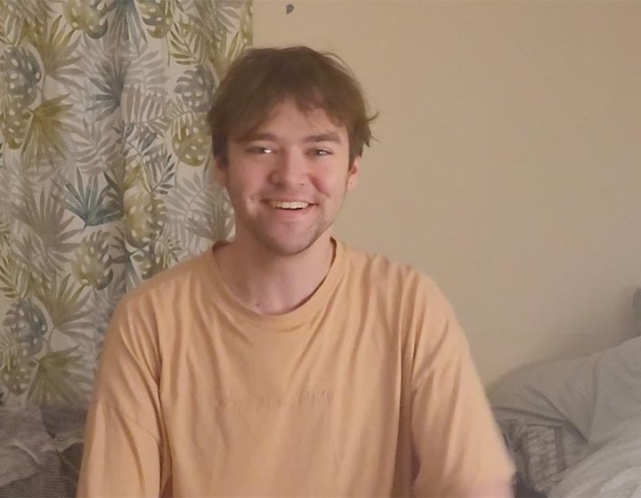 A Graphic Design student sitting in front of leaf-pattern curtains