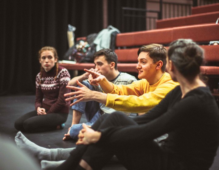 Group of students sat in performance space discussing acting