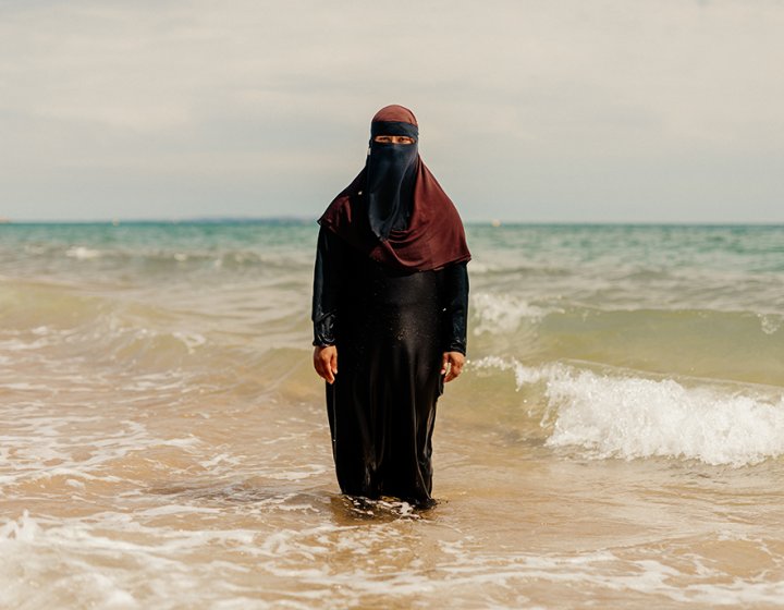 Woman wearing hijab standing in the sea. Portrait of Britain 2023 winning photo by Peter Flude. 