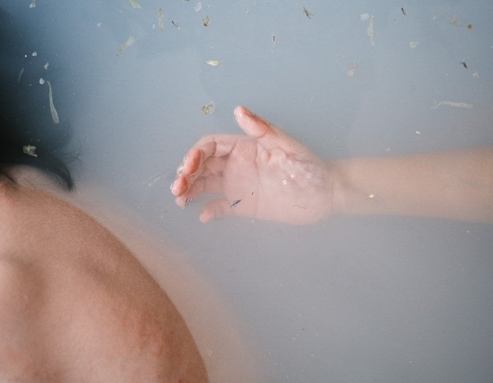 A photograph of a hand in a bathtub of water