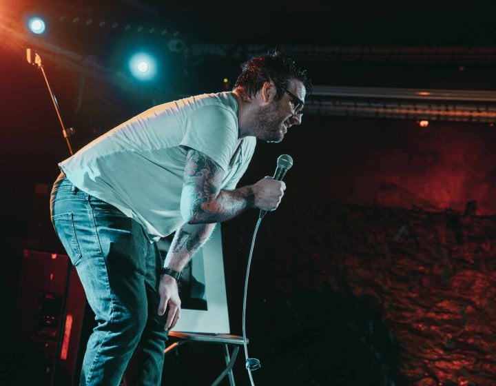 A man on stage performing a stand-up comedy routine