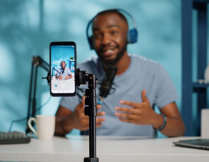 A man wearing headphones filming himself with his phone on a tripod