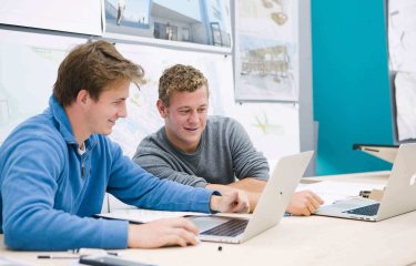 Two male students seated while looking at a laptop