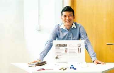 Business & Entrepreneurship student standing at a display table, smiling