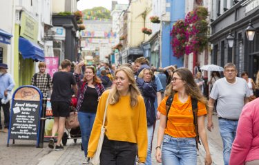 Two students dressed in orange tops walking along Falmouth high street