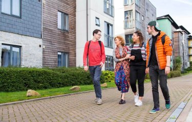 Students walking through Glasney Village with arms linked.