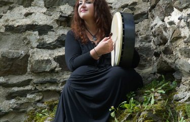 Helen Leahey playing a tambourine on a mountainside
