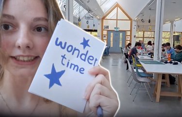 A Graphic Design student holding up her work in the studio at Falmouth University