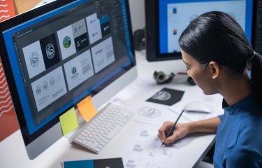 A woman drawing logos at a desktop computer